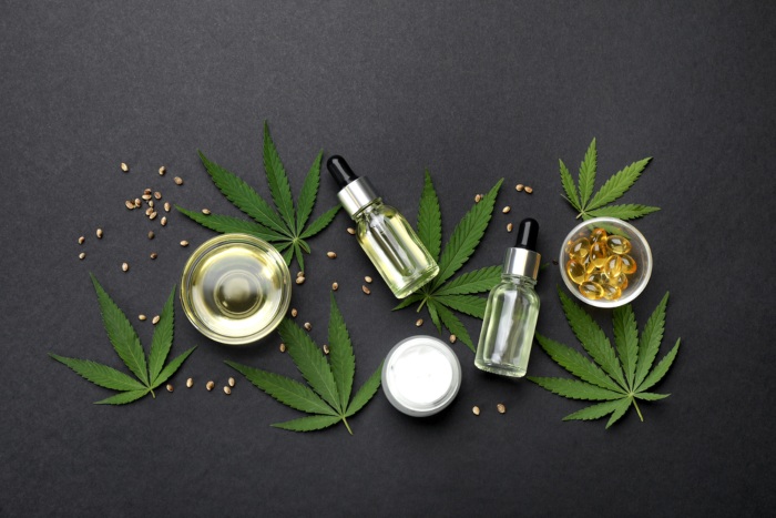 Flat lay composition with hemp leaves, CBD oil and THC tincture on black background